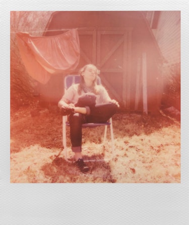 Polaroid of Julien Baker sitting in a lawn chair infront of a barn