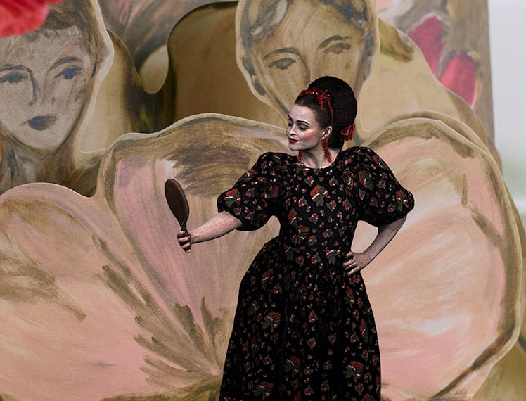 A model in a black-red floral dress by Simone Rocha x HM looking into a hand mirror
