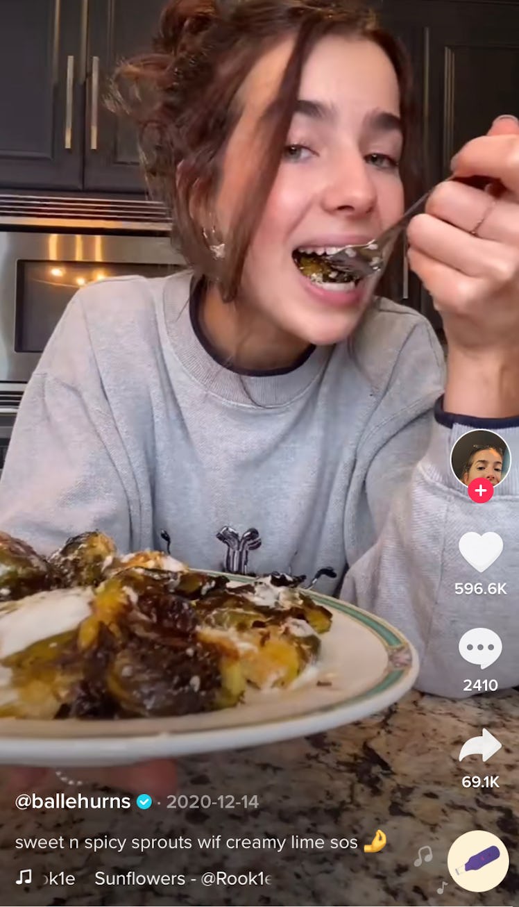 A woman eats some smashed Brussels sprouts in her kitchen. 