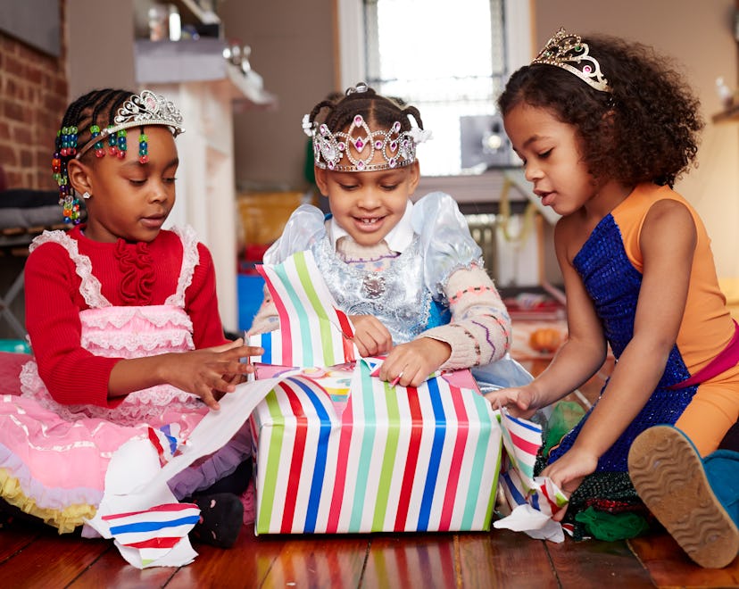 three girls wearing tiaras and opening presents