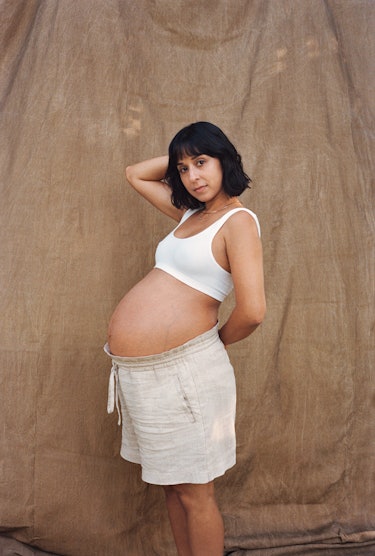 Natalie Tyree in shorts and a white crop top, her pregnant belly center stage 