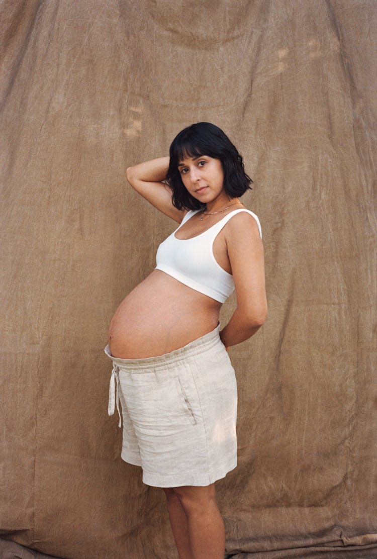 Natalie Tyree in shorts and a white crop top, her pregnant belly center stage 