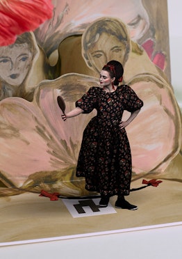 A model in a black-red floral dress by Simone Rocha x HM looking into a hand mirror