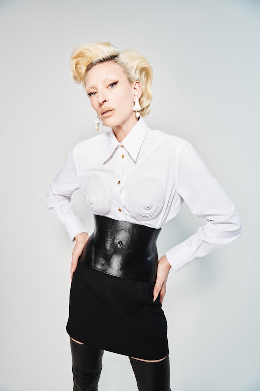 A blonde model posing in a white shirt and in a black skirt