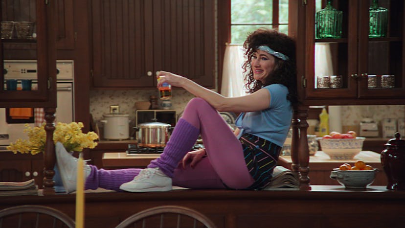 Kathryn Hahn as Agatha, sitting on the kitchen counter in '80s clothes in WandaVision
