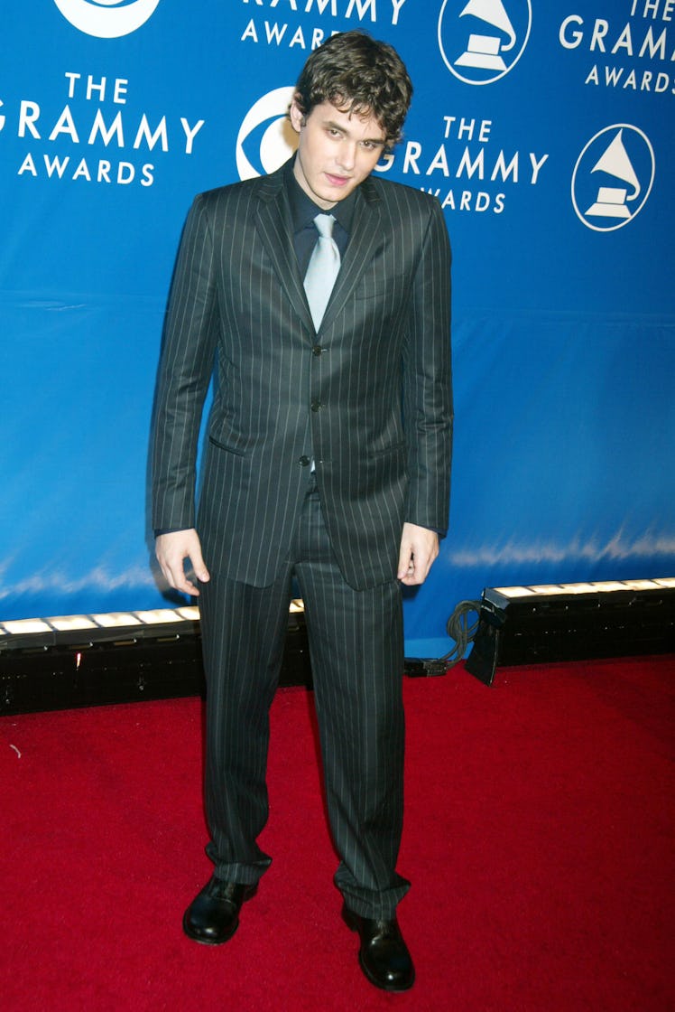 John Mayer wearing a black suit with gray stripes paired with gray tie on a red carpet