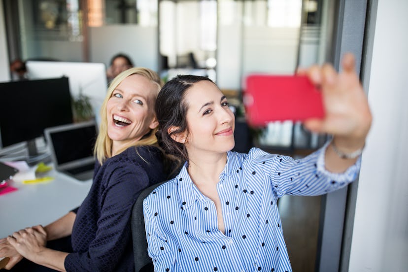 two women with side part taking a selfie in the office
