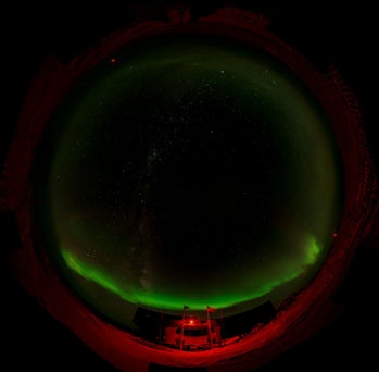 An image of the aurora at night over an Antarctic facility