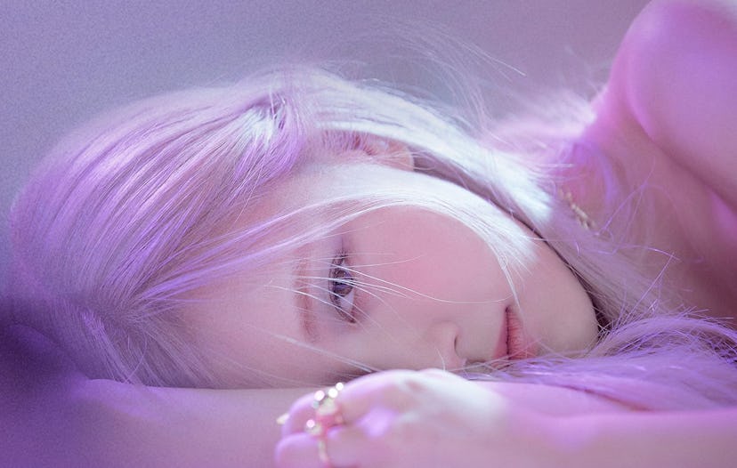 A portrait of Rosé. She is laying down with only half her face exposed, her pink hair dominates the ...