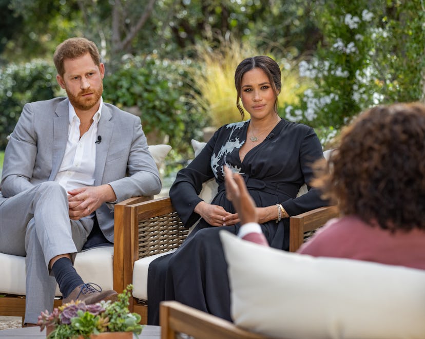 Prince Harry in a grey suit and Meghan Markle in a black dress during their interview with Oprah Win...