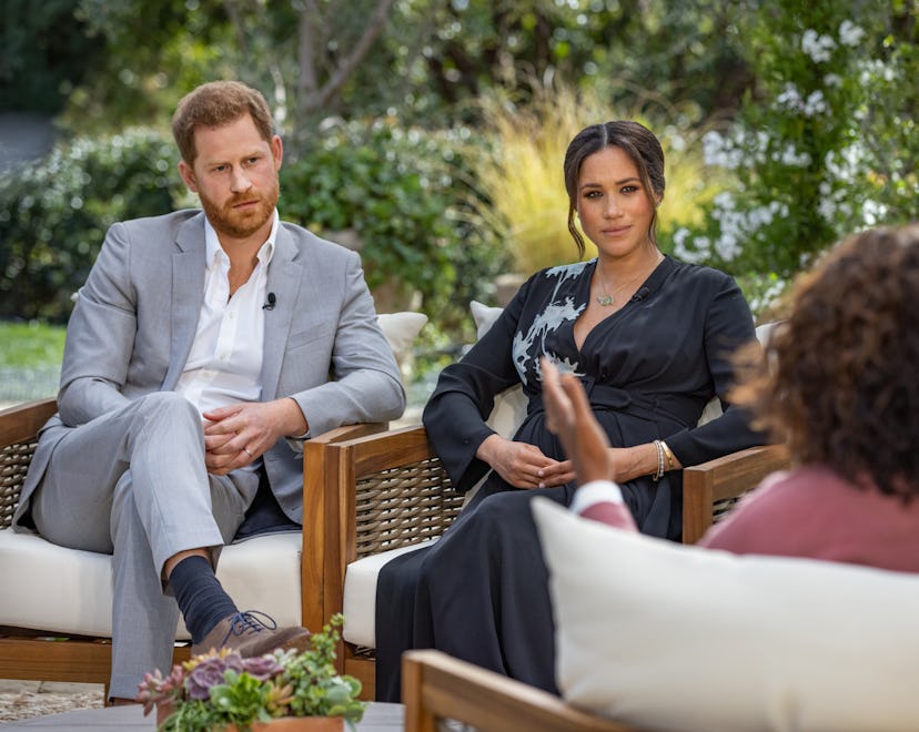 Prince Harry in a grey suit and Meghan Markle in a black dress during their interview with Oprah Win...