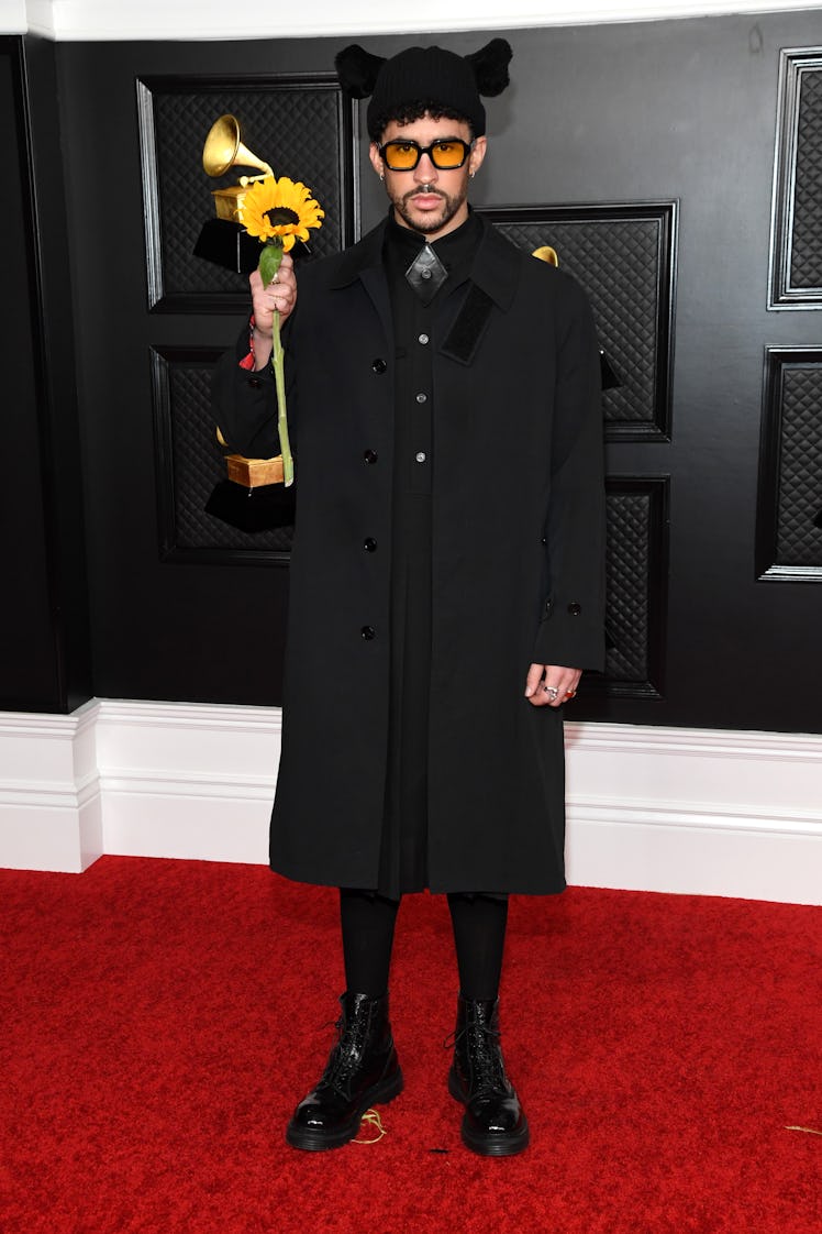 Bad Bunny on the red carpet wearing a large black Burberry coat and holding a sunflower at the 2021 ...