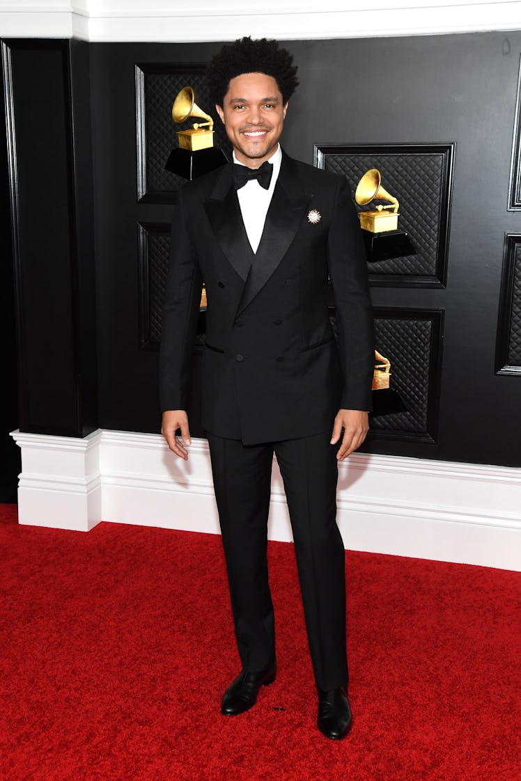 Trevor Noah on the red carpet wearing a black suit at the 2021 Grammys