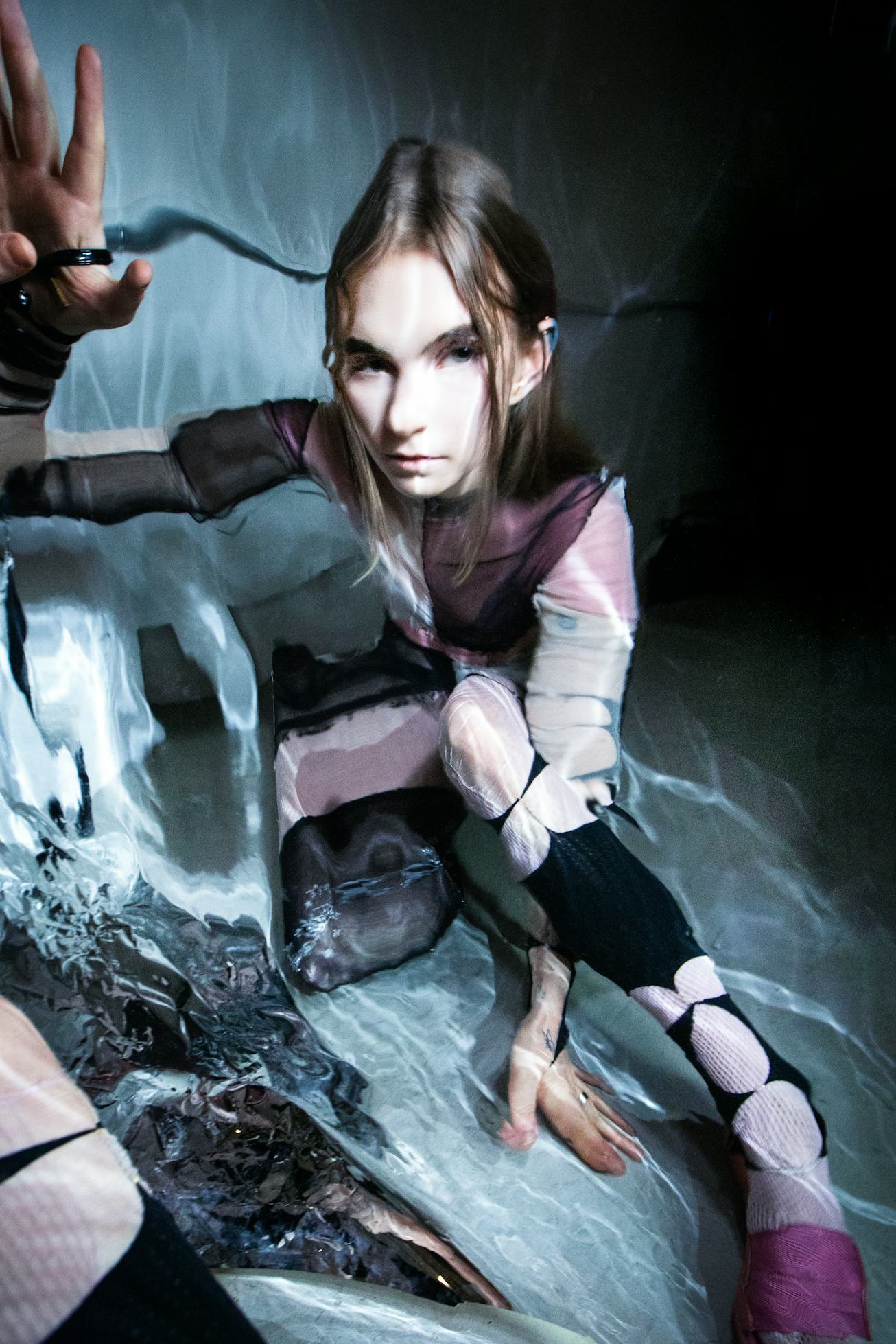 A portrait of James K, which shows her posing against a rippling backdrop that simulates the bottom ...