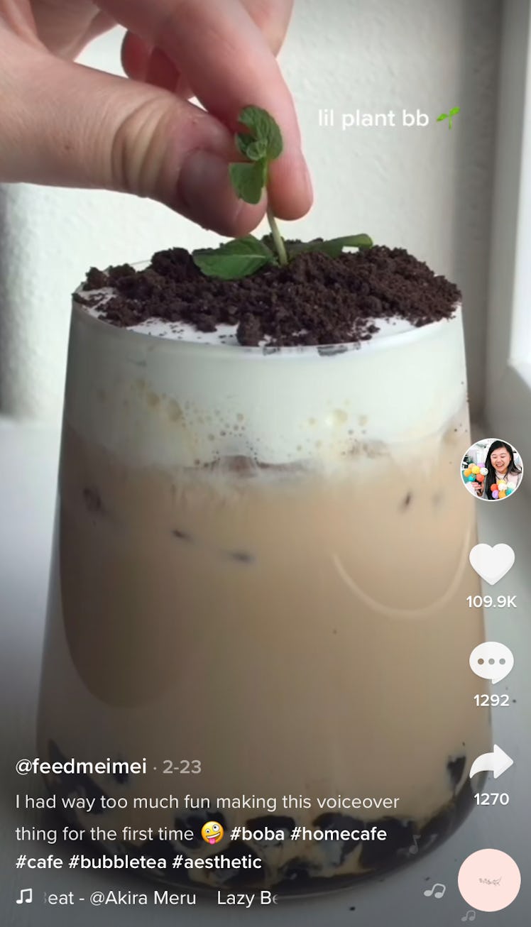 A woman puts a mint leaf into a boba tea drink that looks like a potted plant. 