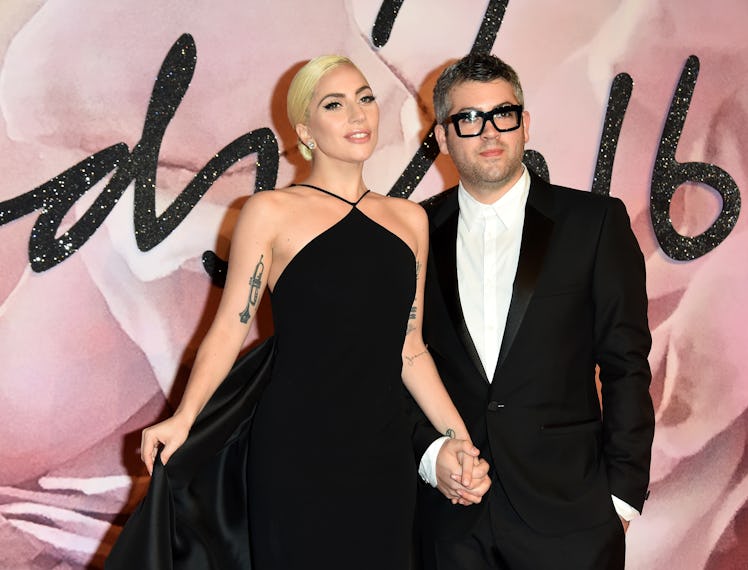 Lady Gaga in a black gown and Brandon Maxwell in a white shirt, and a black blazer at a red carpet e...
