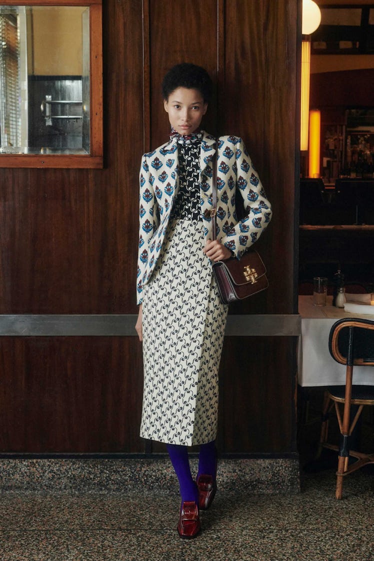 A model in mixed print skirt, blazer, and shirt by Tory Burch