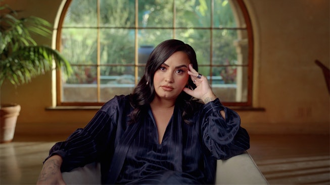 Demi Lovato sits in a chair during filming of Demi Lovato: Dancing With the Devil documentary