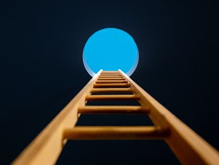 A ladder leading to a circular opening showing the blue sky