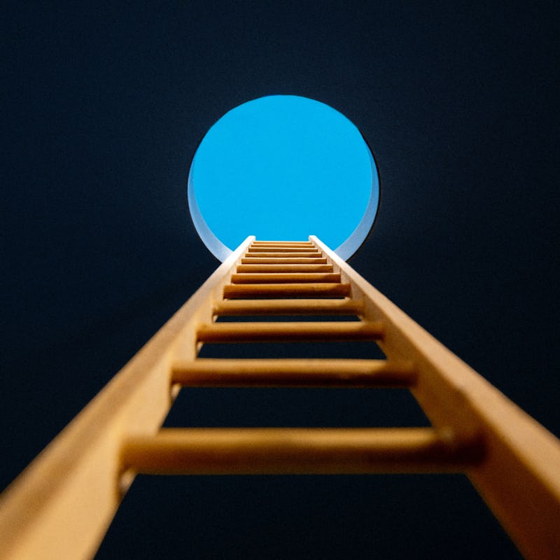 A ladder leading to a circular opening showing the blue sky