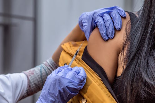 A nurse moves to administer the COVID vaccine on a woman. Community outreach programs working on exp...