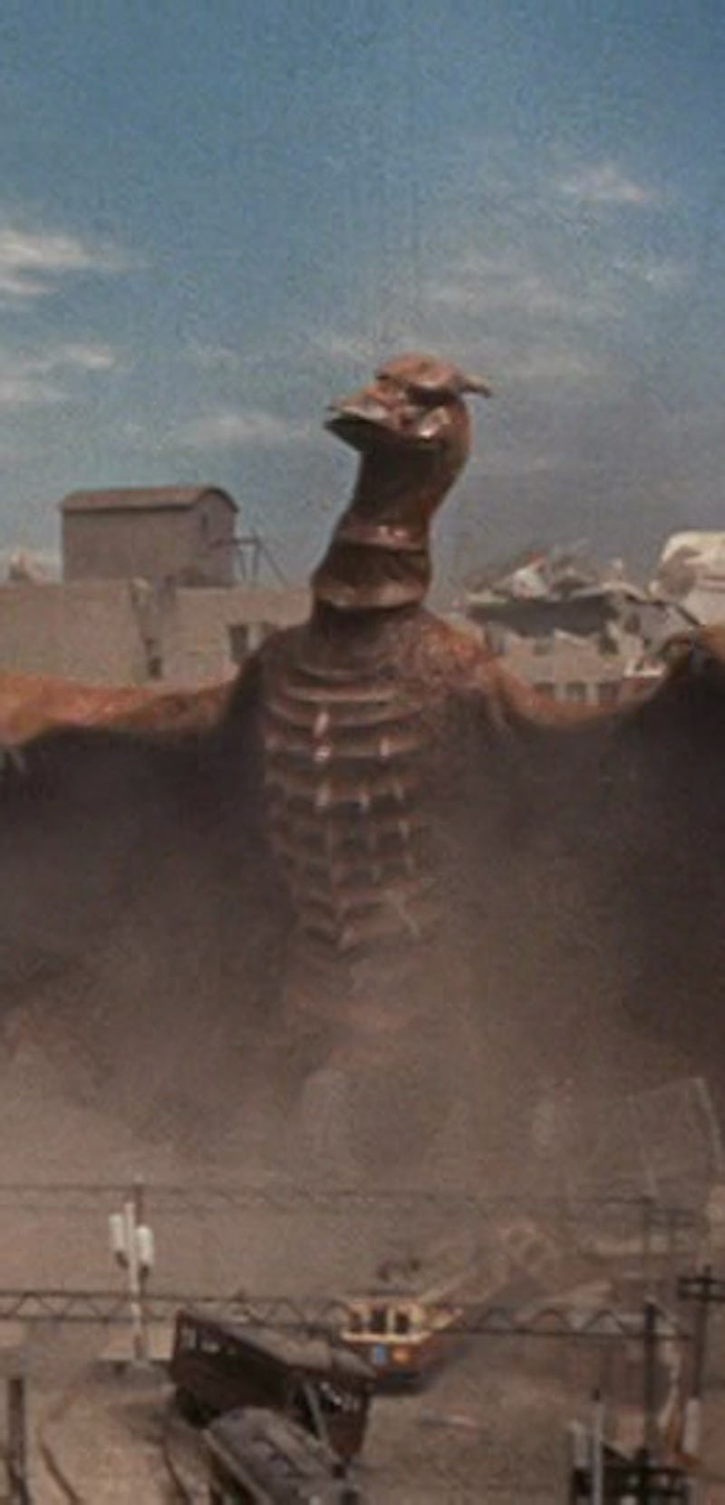rodan monster destroying city with ruined building models in background