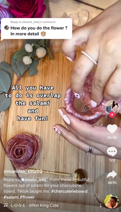 A woman makes roses out of sliced meat for her charcuterie board. 