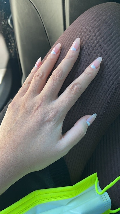 Closeup of Chrissy Teigen's hand with her new half moon manicure in, with blue on the top corner of ...