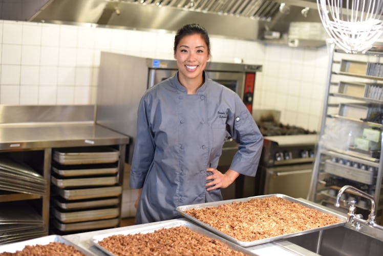 An image of a woman standing over a baking tray full of granola
