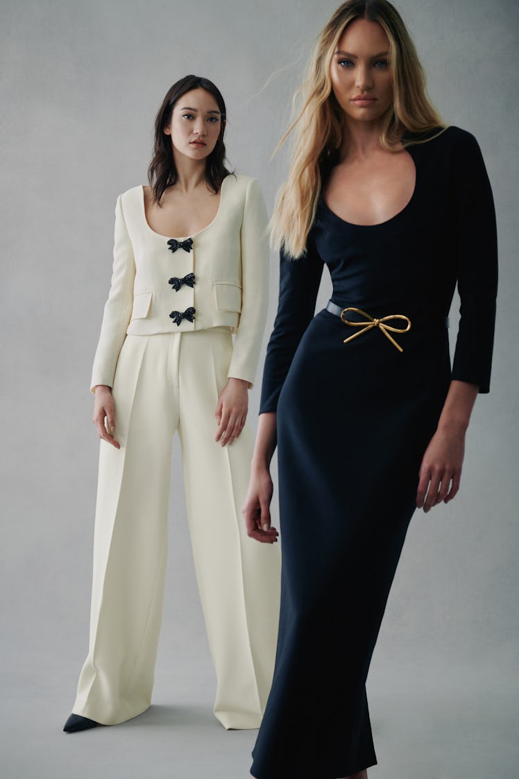 A model in a white suit with black bows and a model in a black dress with a gold bow by Oscar de la ...