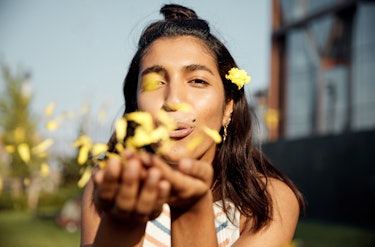 Młoda kobieta dmuchająca kwiaty; podpisy pod kwiatami na instagram, podpisy pod kwiatami, podpis pod kwiatami
