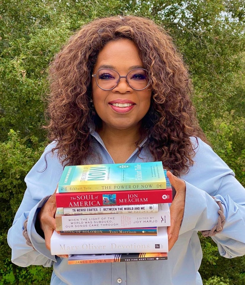 Oprah holding a stack of books.