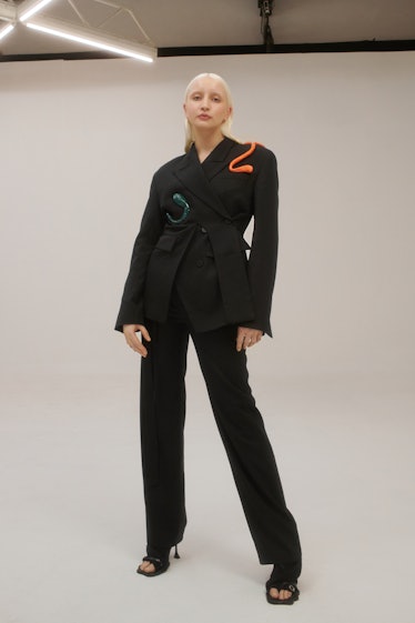A blonde lady posing in a combination of a black blazer and pants