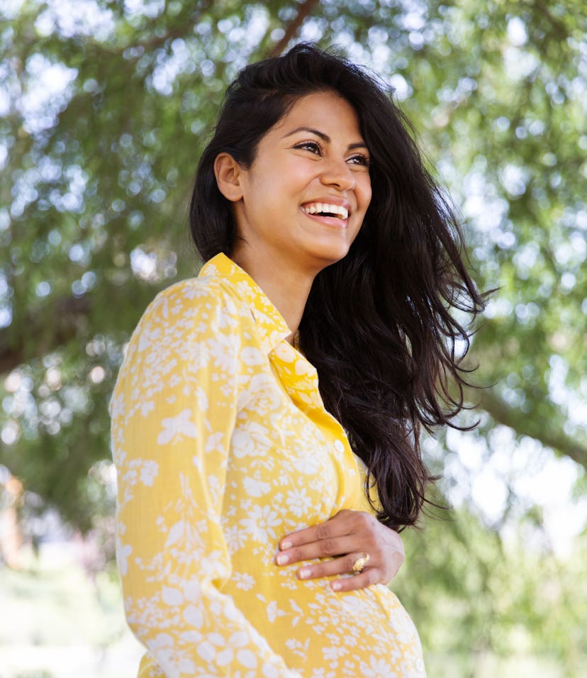 smiling pregnant woman wearing yellow floral blouse