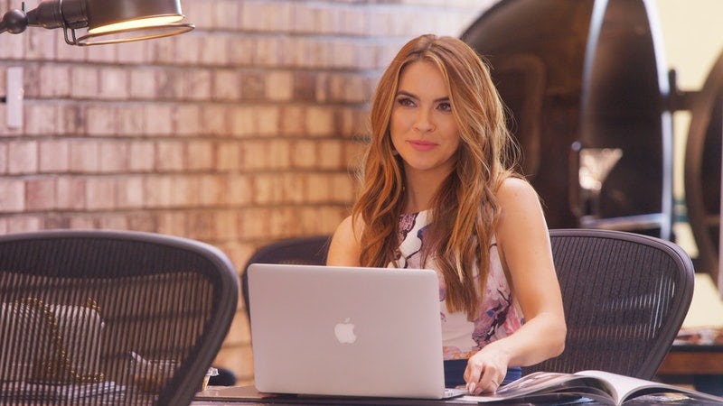 Chrishell Stause sits behind her laptop at her desk in the Oppenheim Group office