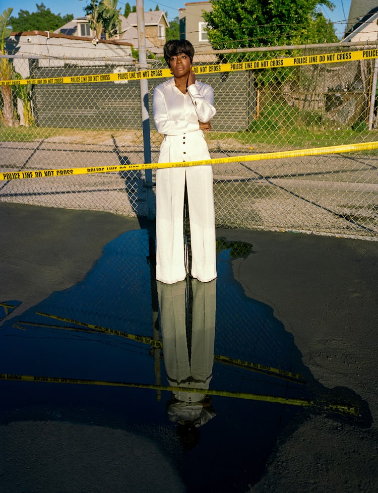 Viola Davis standing inside the Do Not Cross police tape in white pants and a shirt
