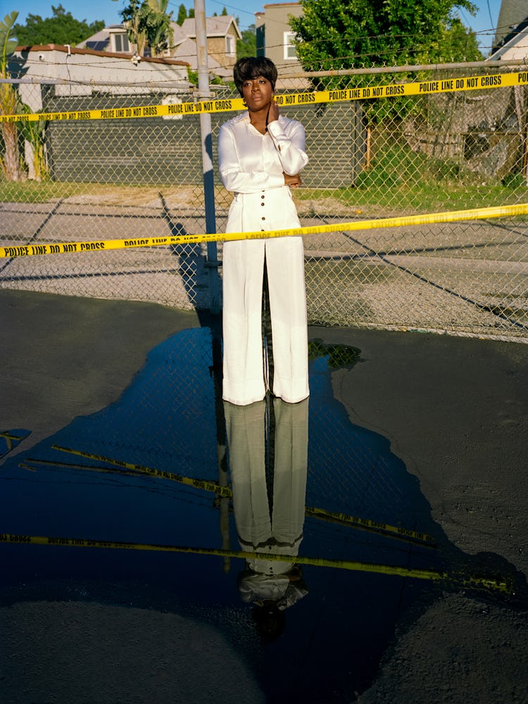 Viola Davis standing inside the Do Not Cross police tape in white pants and a shirt
