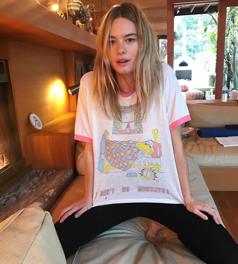 Camille Rowe posing at her home in a casual outfit wearing black leggings and a fun colorful Donald ...