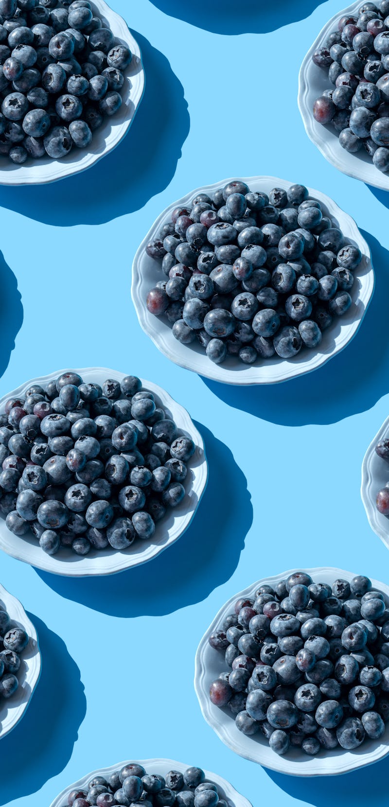 Blueberries in white bowls lined up on a table