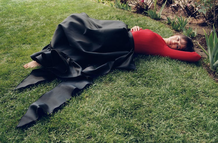 Rashida Jones lying on the grass in a black maxi skirt and red top