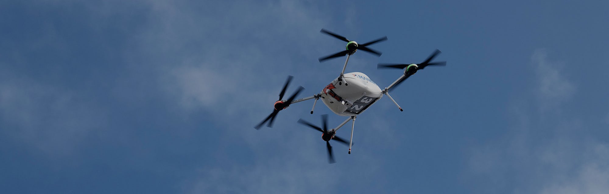 A Manna drone carrying a Samsung product is seen hovering in the air.