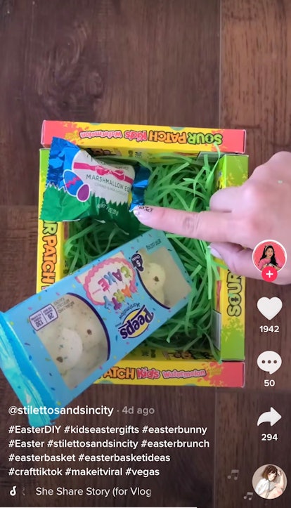 A woman fills up an Easter basket made out of candy boxes. 