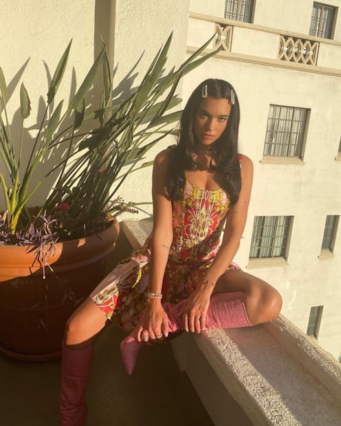 Dua Lipa poses in a red, pink, and gold dress.