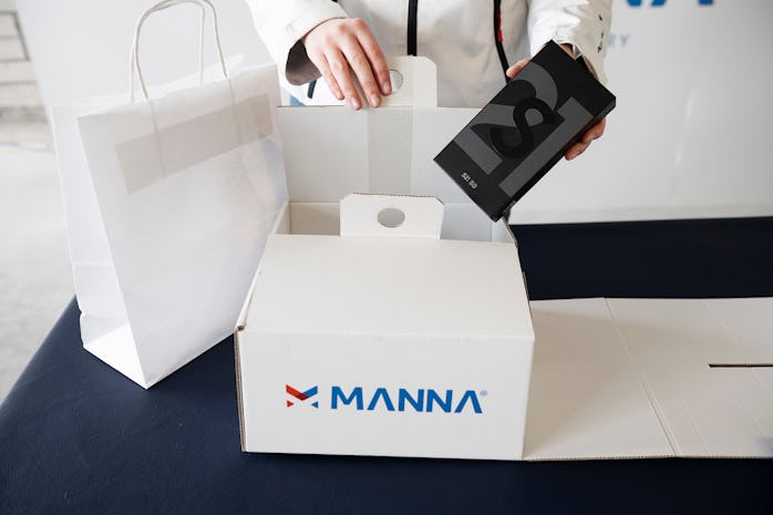 A pair of hands approach a box with the title Manna on it. This box has a Samsung gadget inside. 