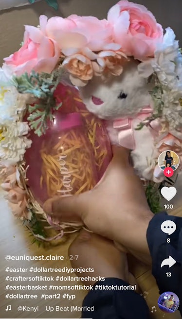 A woman fills up an Easter egg made out of string and fake flowers. 