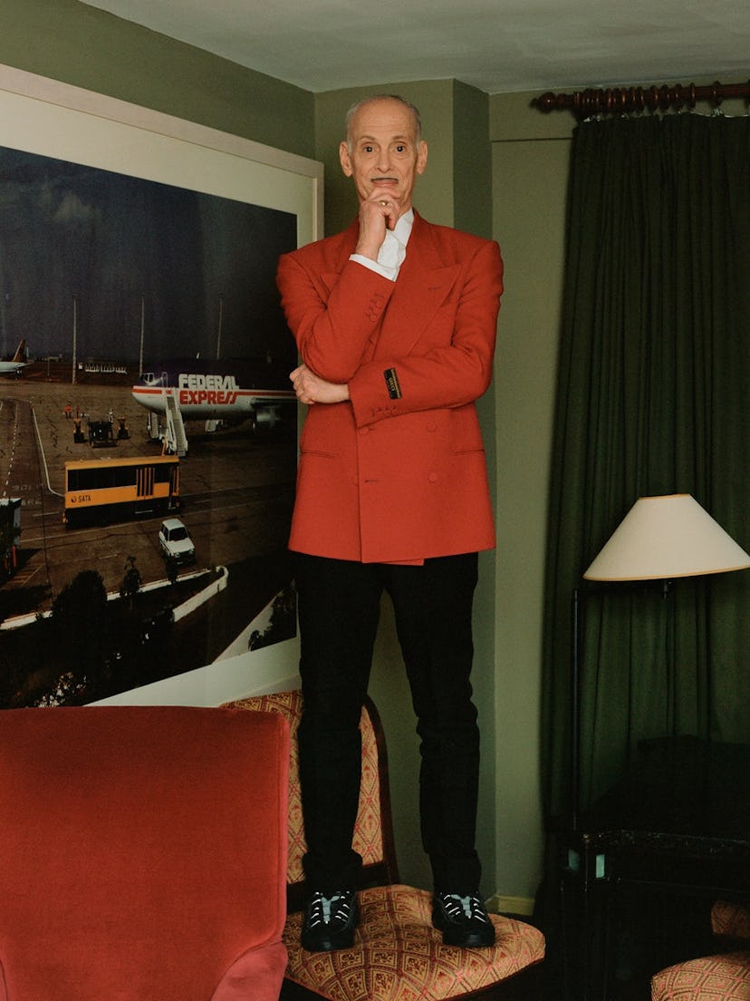 John Waters standing on a chair