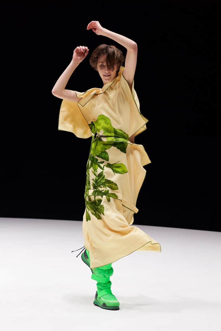 A model dancing in a Kenzo show in a beige floral dress and green boots 