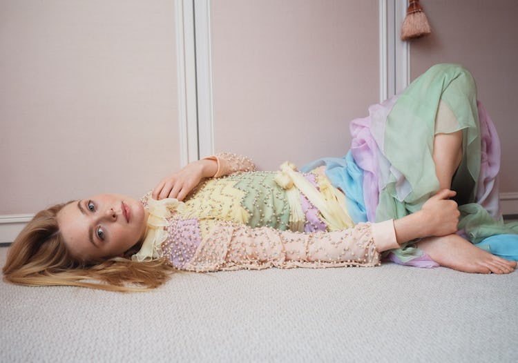 Elle Fanning lying on the floor in a colorful beaded maxi dress