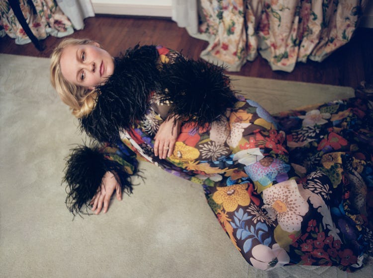 Kirsten Dunst lying on the floor while wearing a colorful maxi dress with black faux fur details