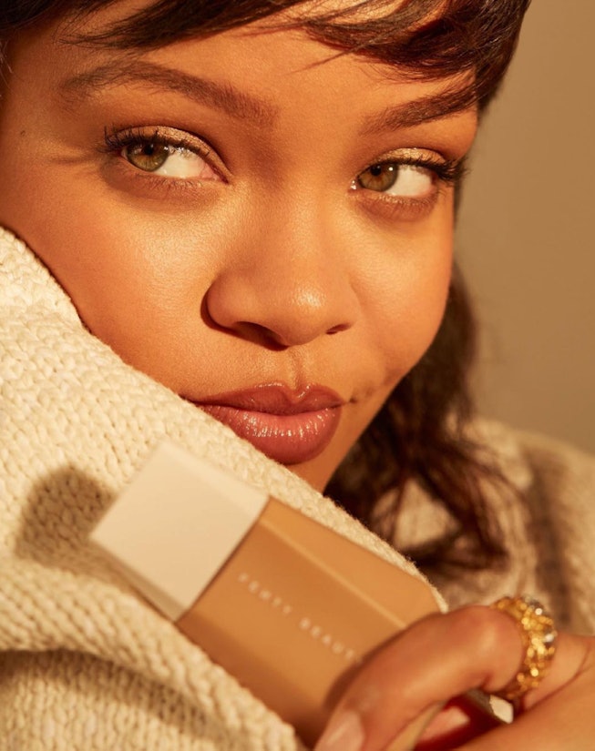 Rihanna holds bottle of Fenty Beauty Eaze Drop Blurring Skin Tint
